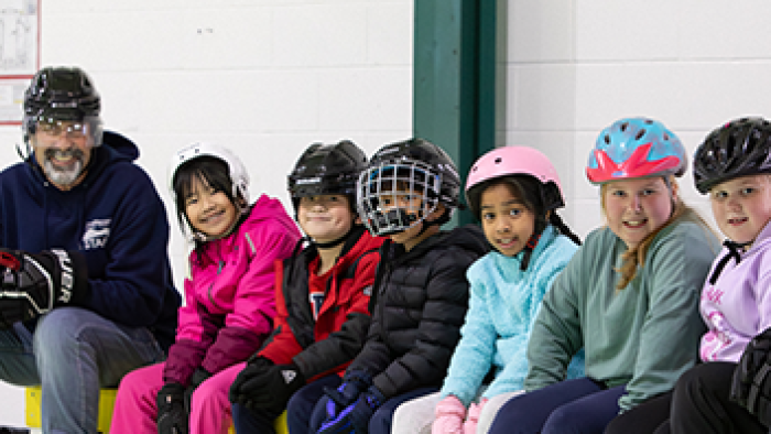 Children with helmets on sitting on the edge of the Leisure Ice