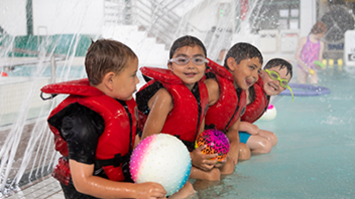 Children in lifejackets sitting on the edge of the Leisure Pool