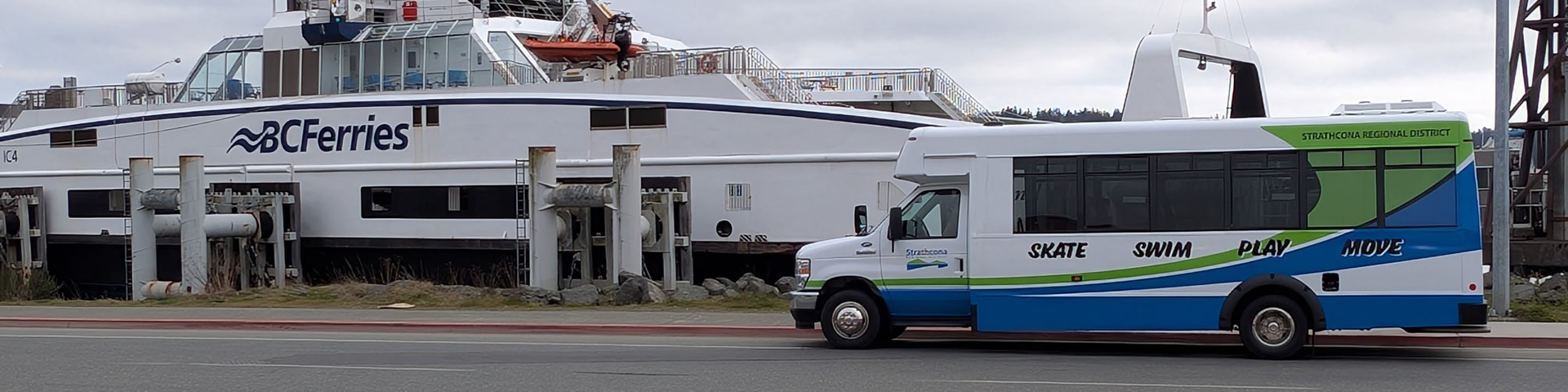 A shuttle bus parked near a large ferry docked at the terminal.