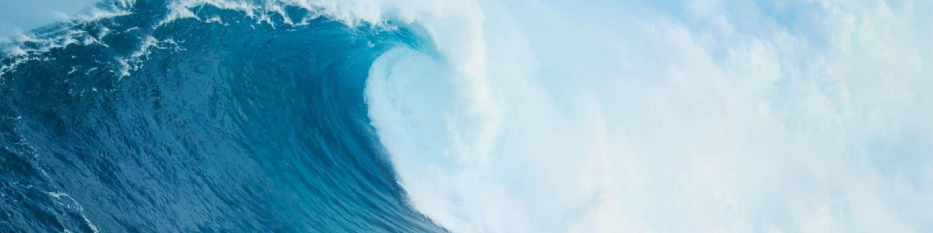 Large ocean wave crashing with blue and white frothy water.