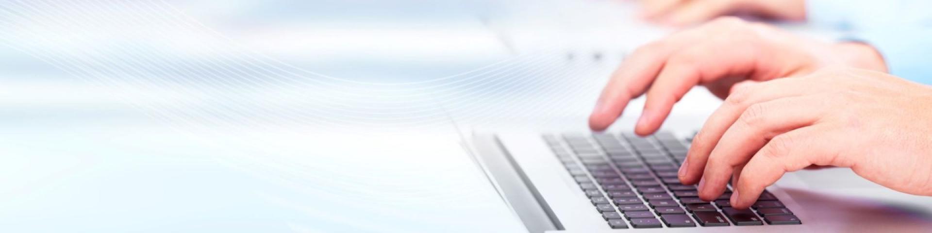 Hands typing on laptop keyboard.