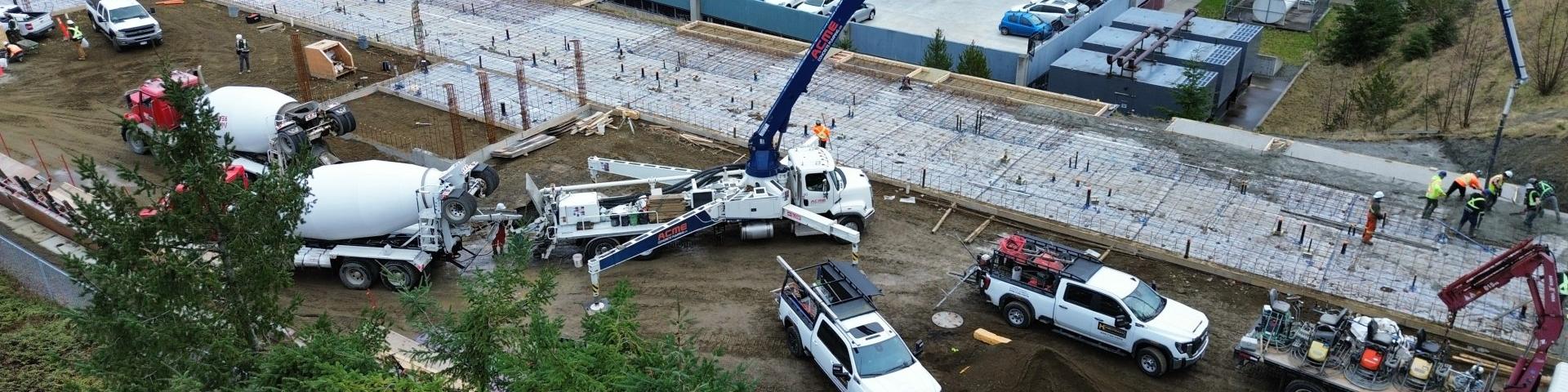 Construction site with concrete trucks and machinery pouring concrete for a new foundation.