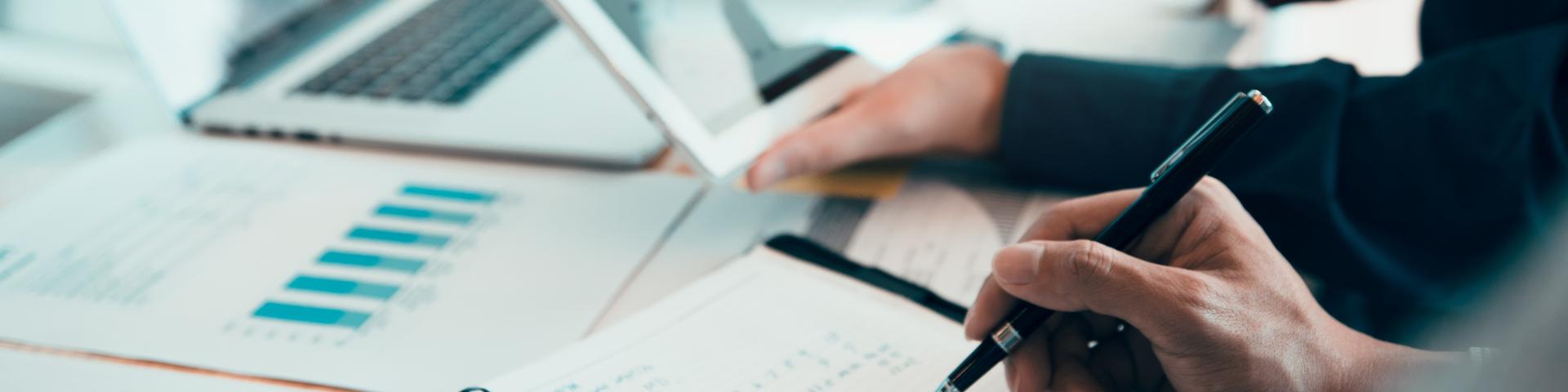 Hands engaged in discussion over notebooks and laptops, analyzing data and notes.