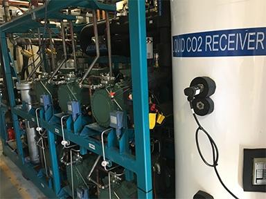Industrial equipment with blue piping and large CO2 tank.