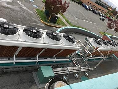 Industrial rooftop cooling units with visible fans and surrounding piping.