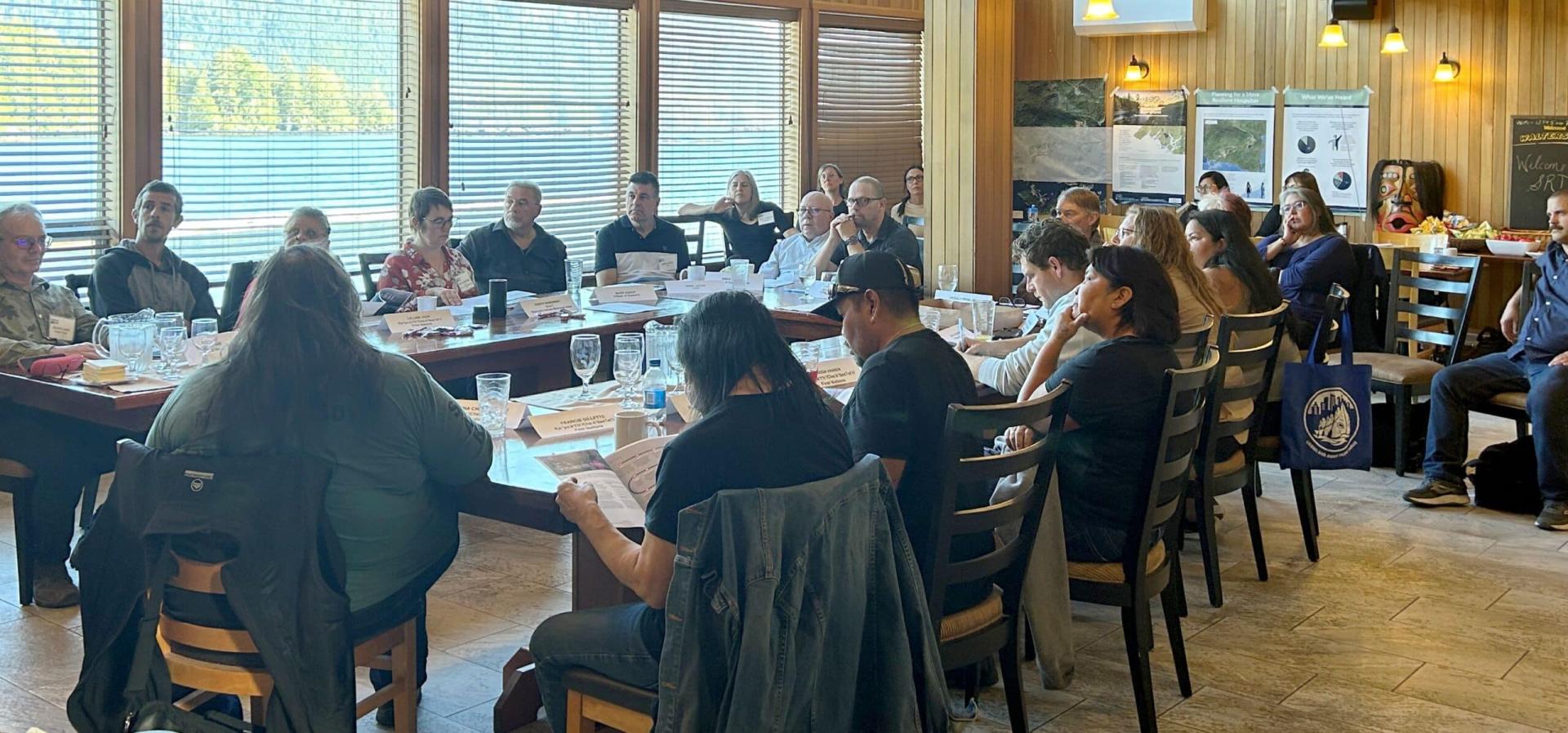 Meeting in a large room with people seated around a long table.